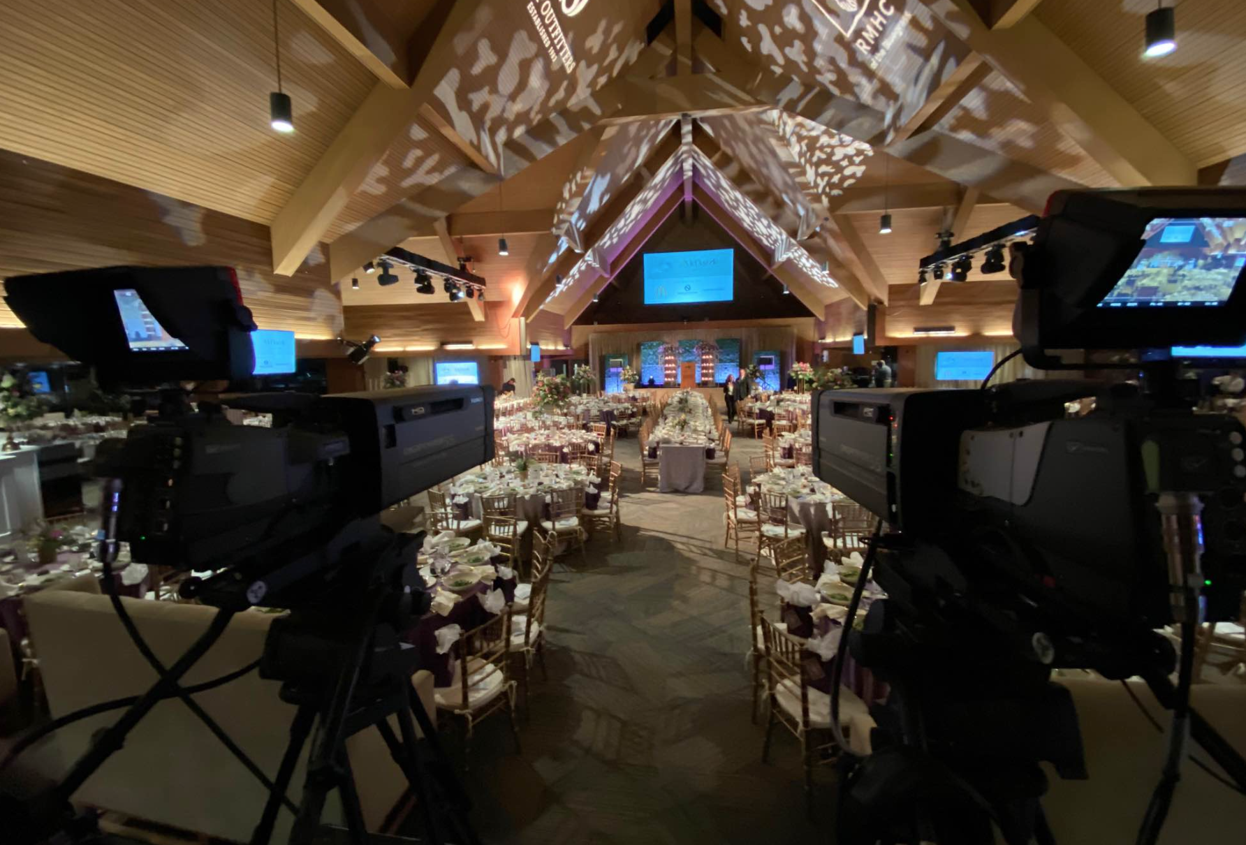 State of the art videography equipment facing out towards a banquet room set up for a formal dinner.